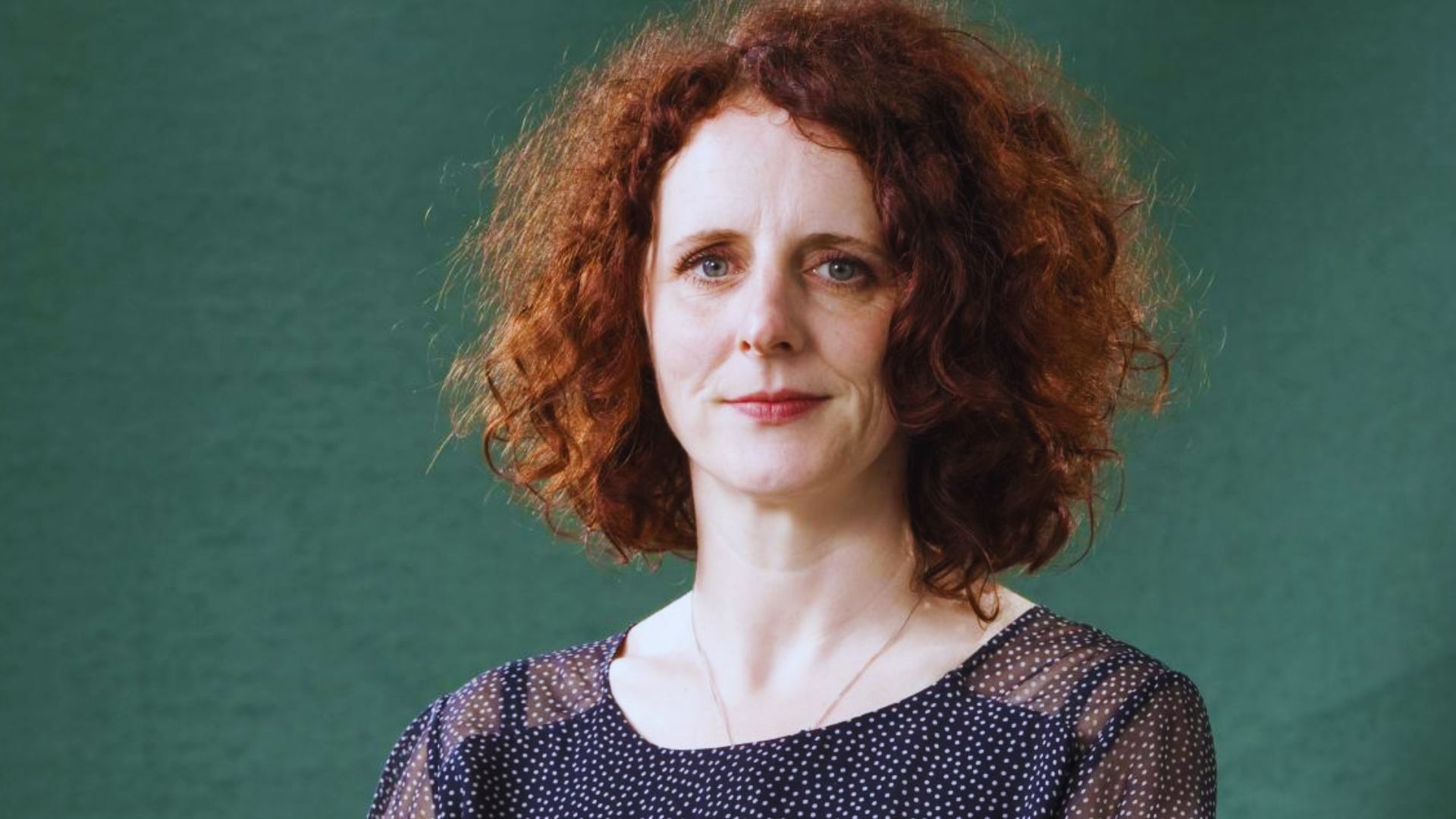 A woman with vibrant red hair in a blue shirt, identified as author Maggie O'Farrell.