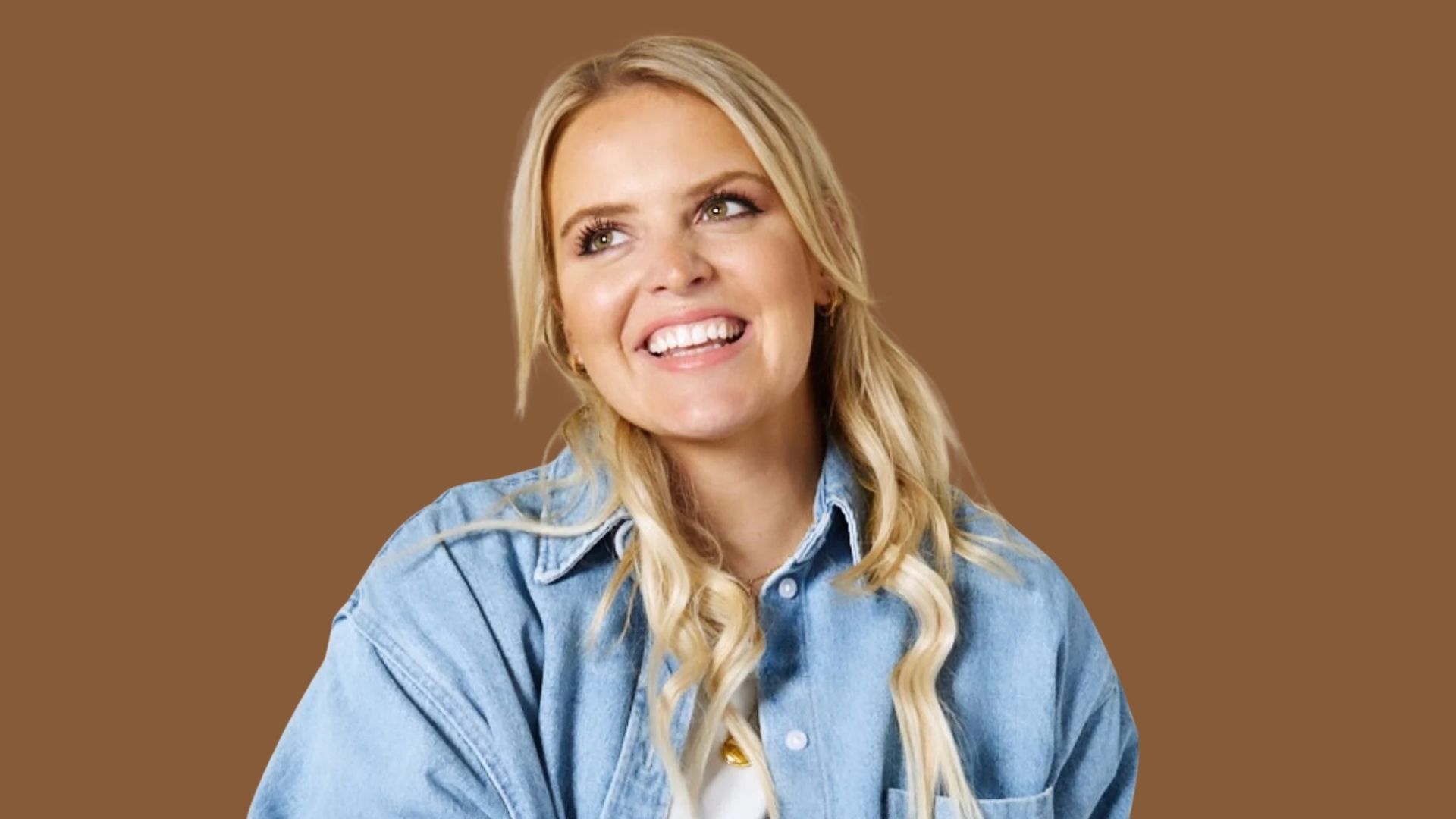 A woman with blonde hair in a blue shirt, posing against a neutral background with a friendly demeanor.