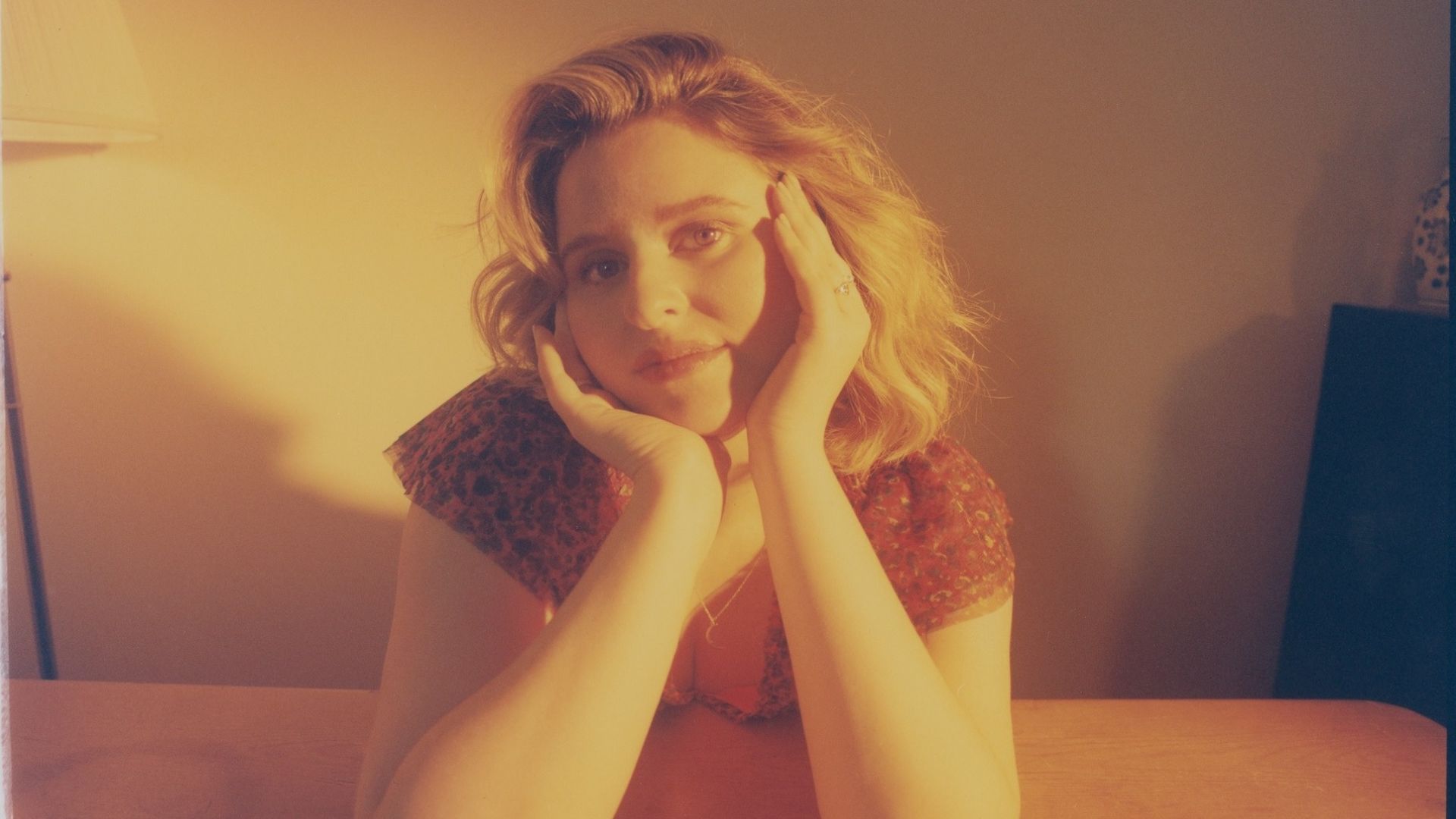 A woman at a table with her hands on her face, conveying a sense of worry or reflection.
