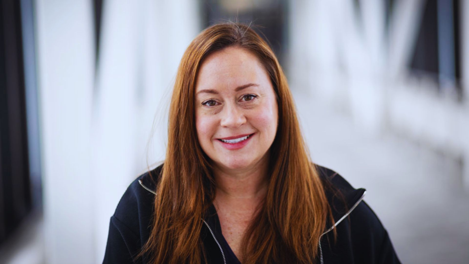 Shelby Van Pelt, a woman with long red hair, smiles brightly, embodying her vibrant personality as a writer.