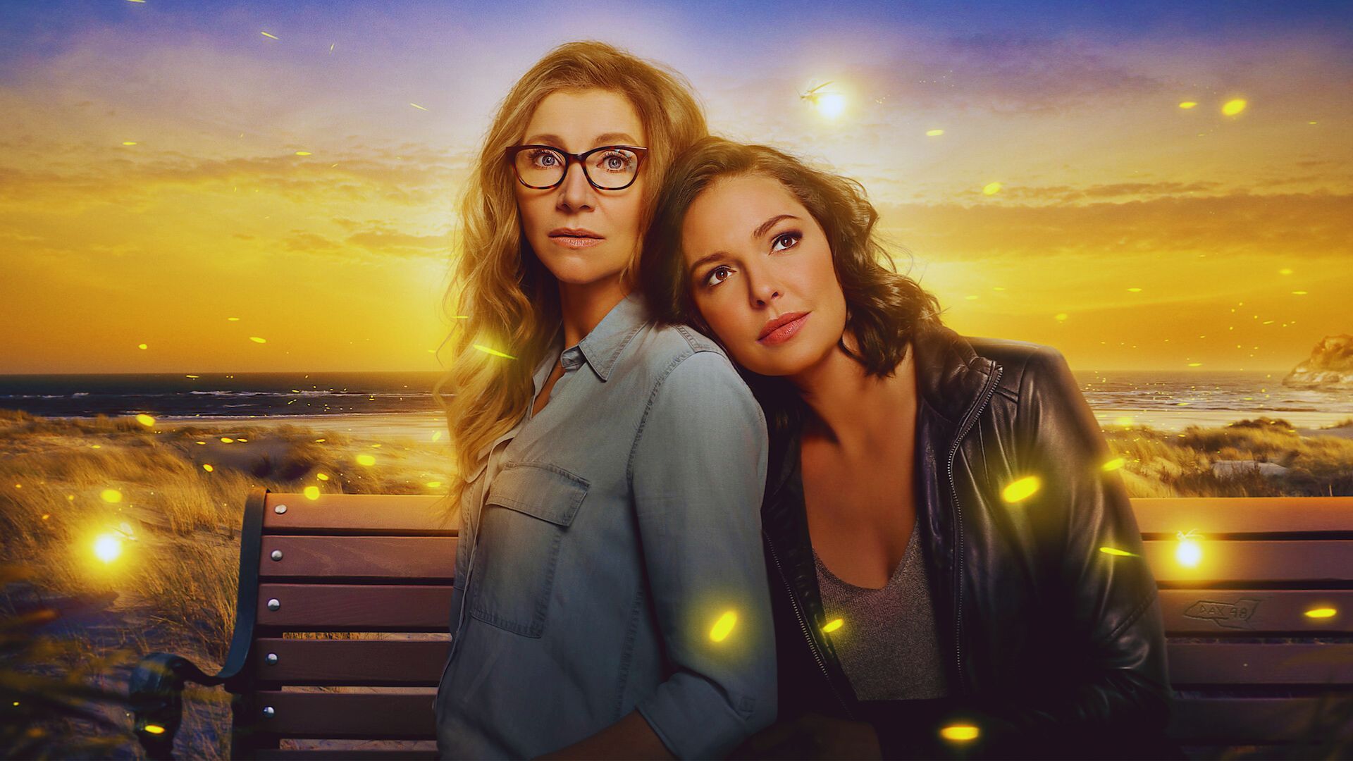 Two women sit on a bench, surrounded by glowing fireflies in a serene evening setting.