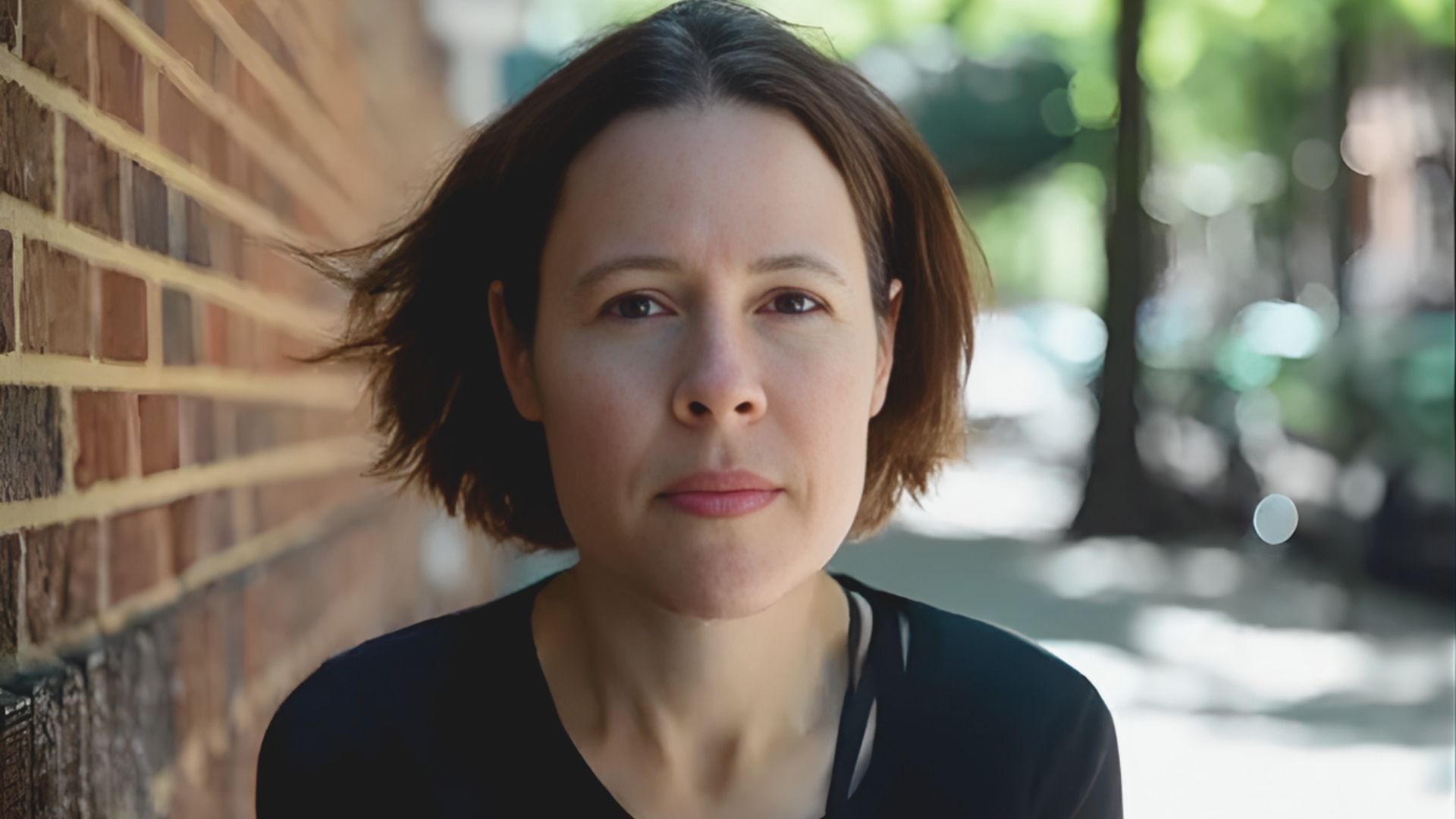 A woman with short hair in a black shirt, posing with a relaxed expression in a casual setting.
