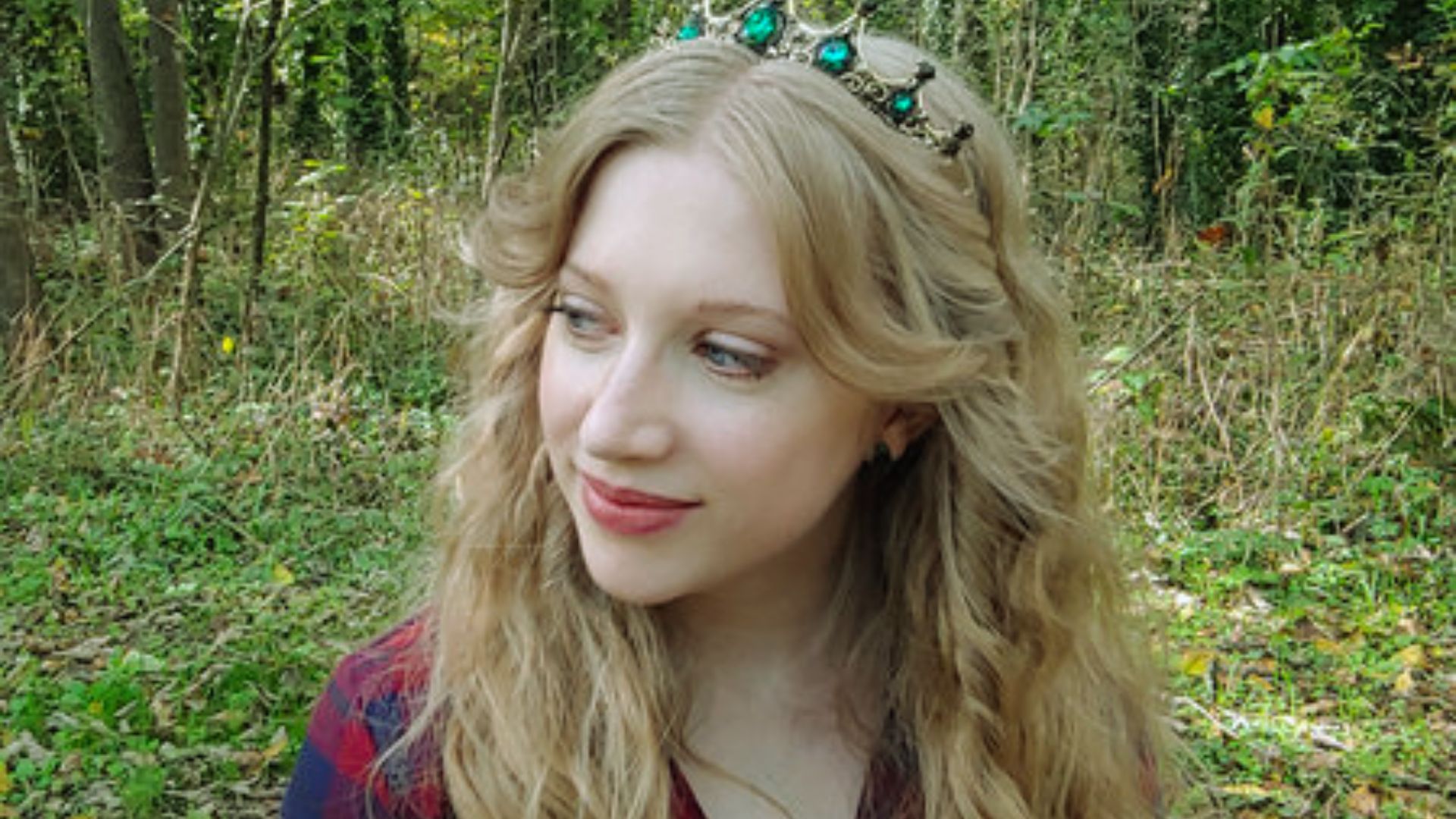 A woman with long blonde hair wearing an ornate crown, exuding elegance and regality.