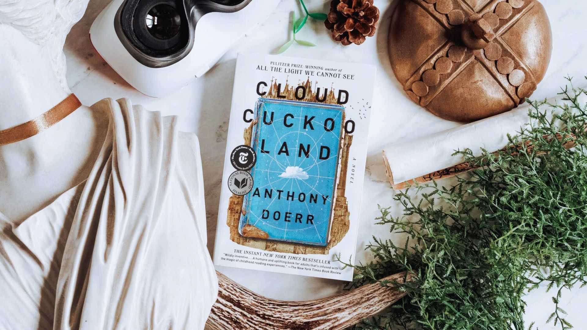 Cover of "Cloud Cuckoo Land" by Anthony Doerr, featuring a whimsical illustration of clouds and a serene landscape.