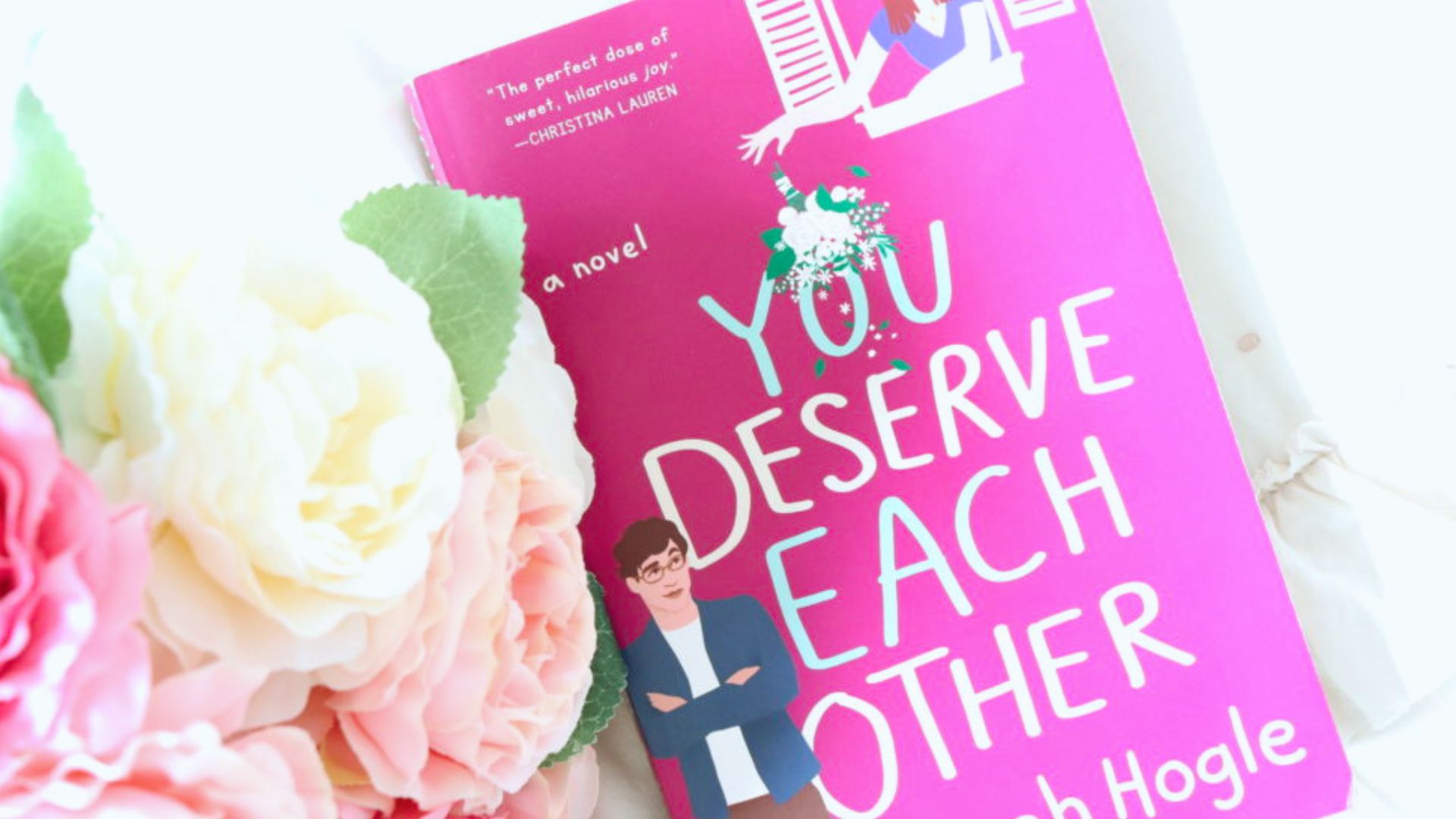 You Deserve Each Other" by Rob Hogg cover, depicting a joyful couple in a lighthearted pose with a bright, cheerful backdrop.