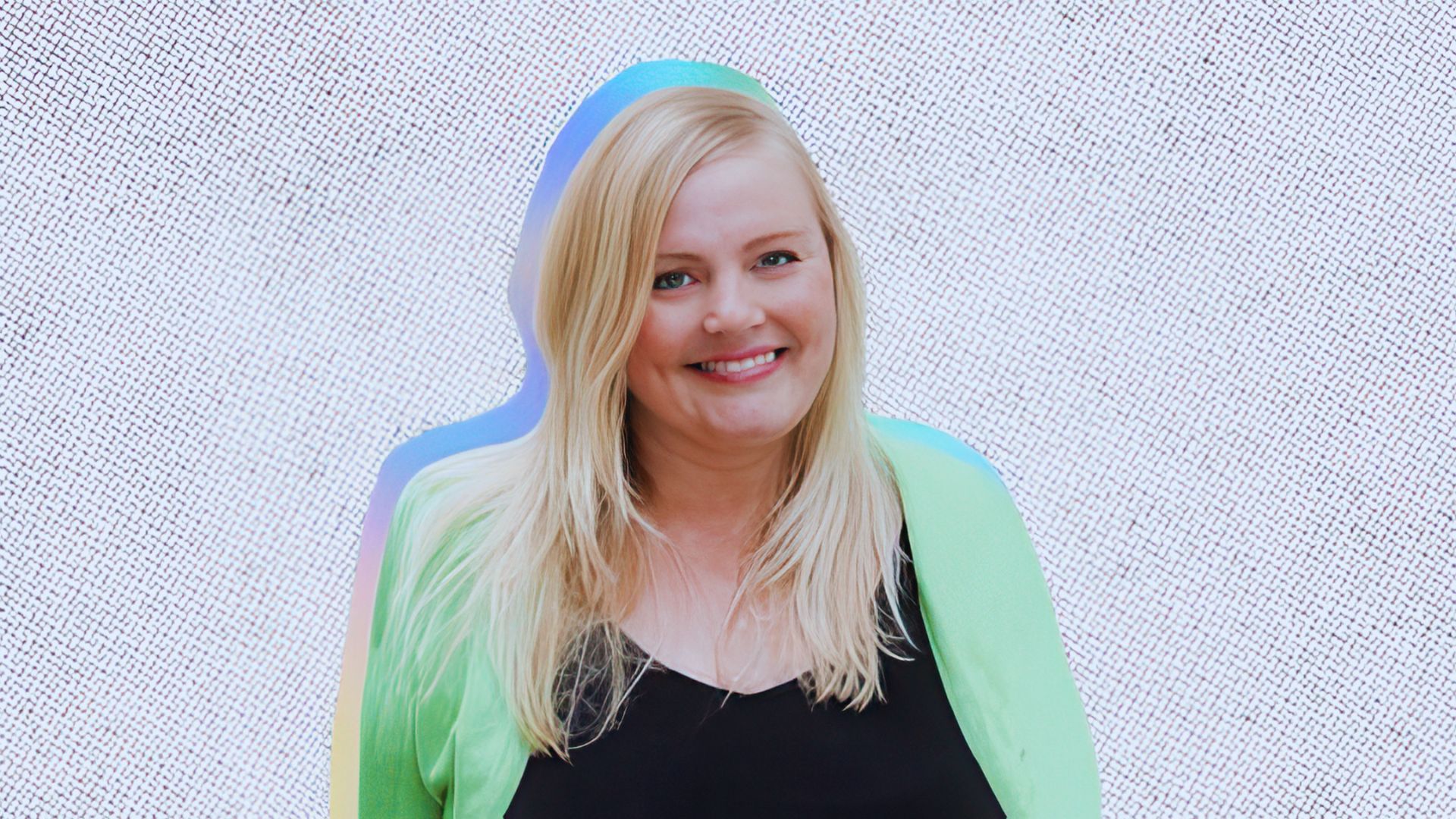 A woman with blonde hair wearing a green jacket stands confidently, smiling at the camera.