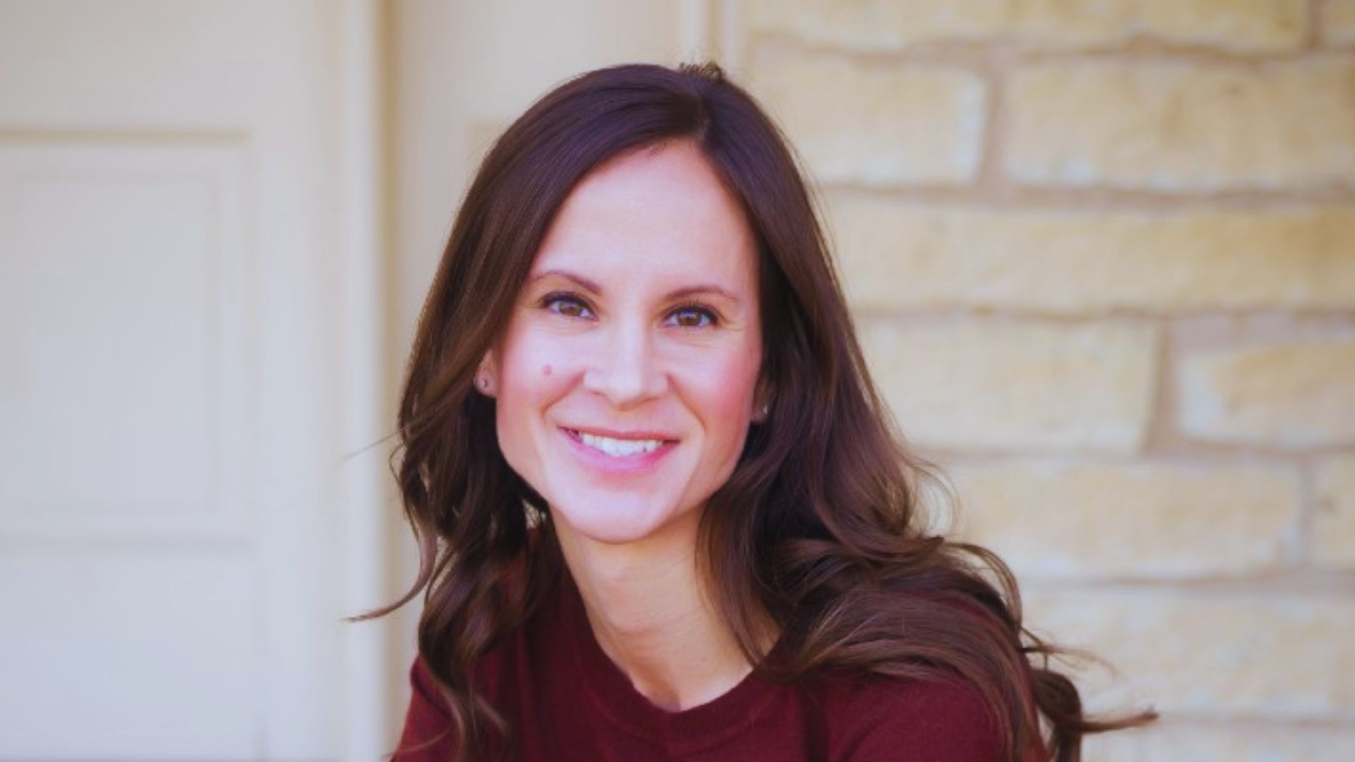 A woman with long brown hair displays a cheerful smile, exuding happiness.