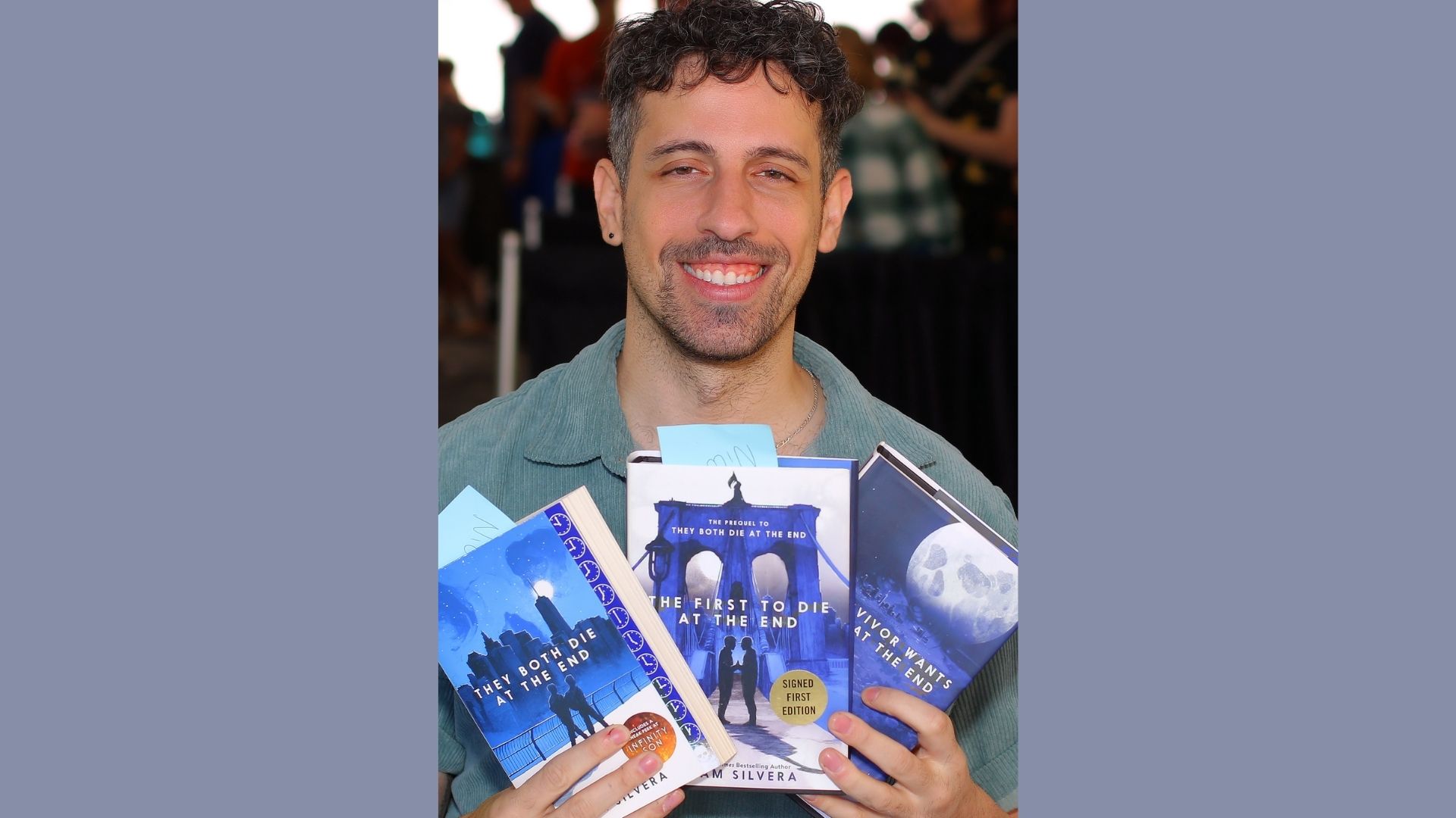A man stands holding three books in front of him, showcasing his interest in reading or studying.