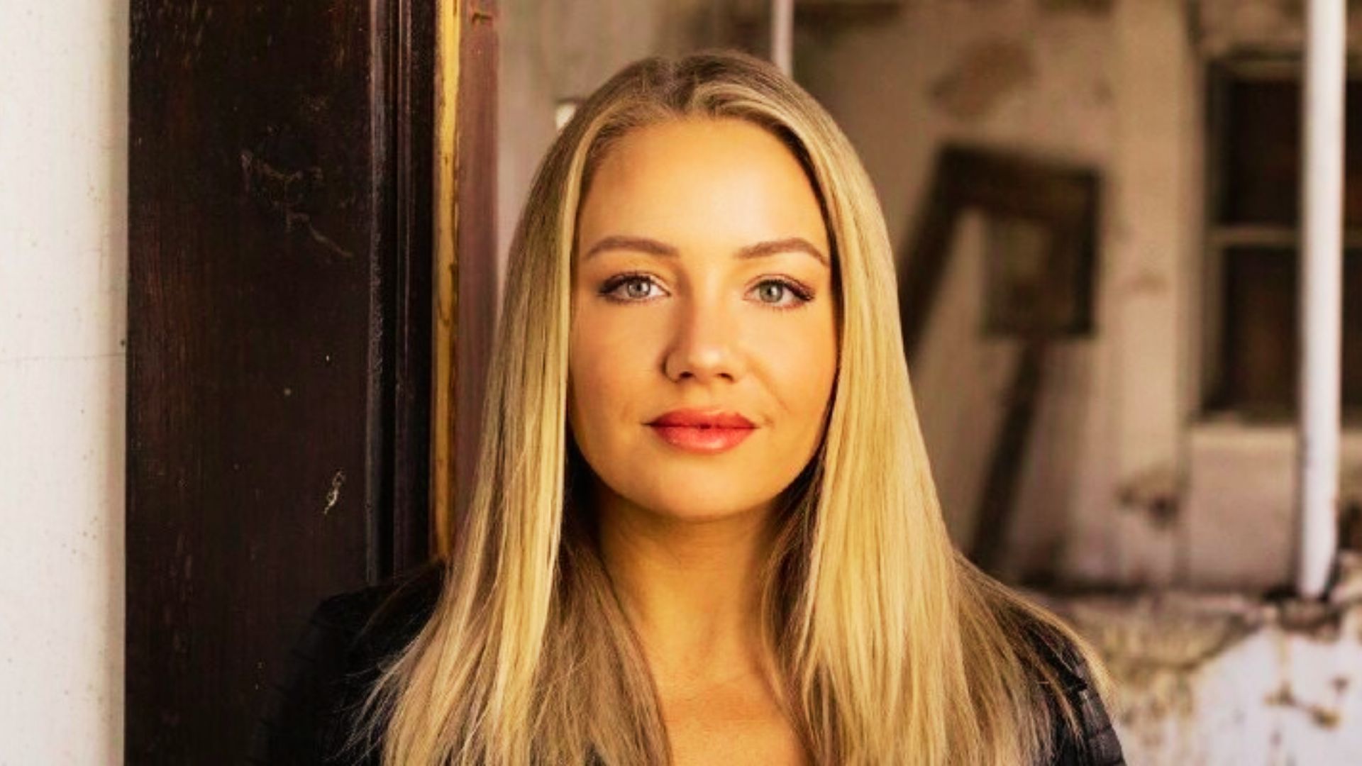 A woman with long blonde hair wearing a black jacket, representing the author Jeneva Rose.