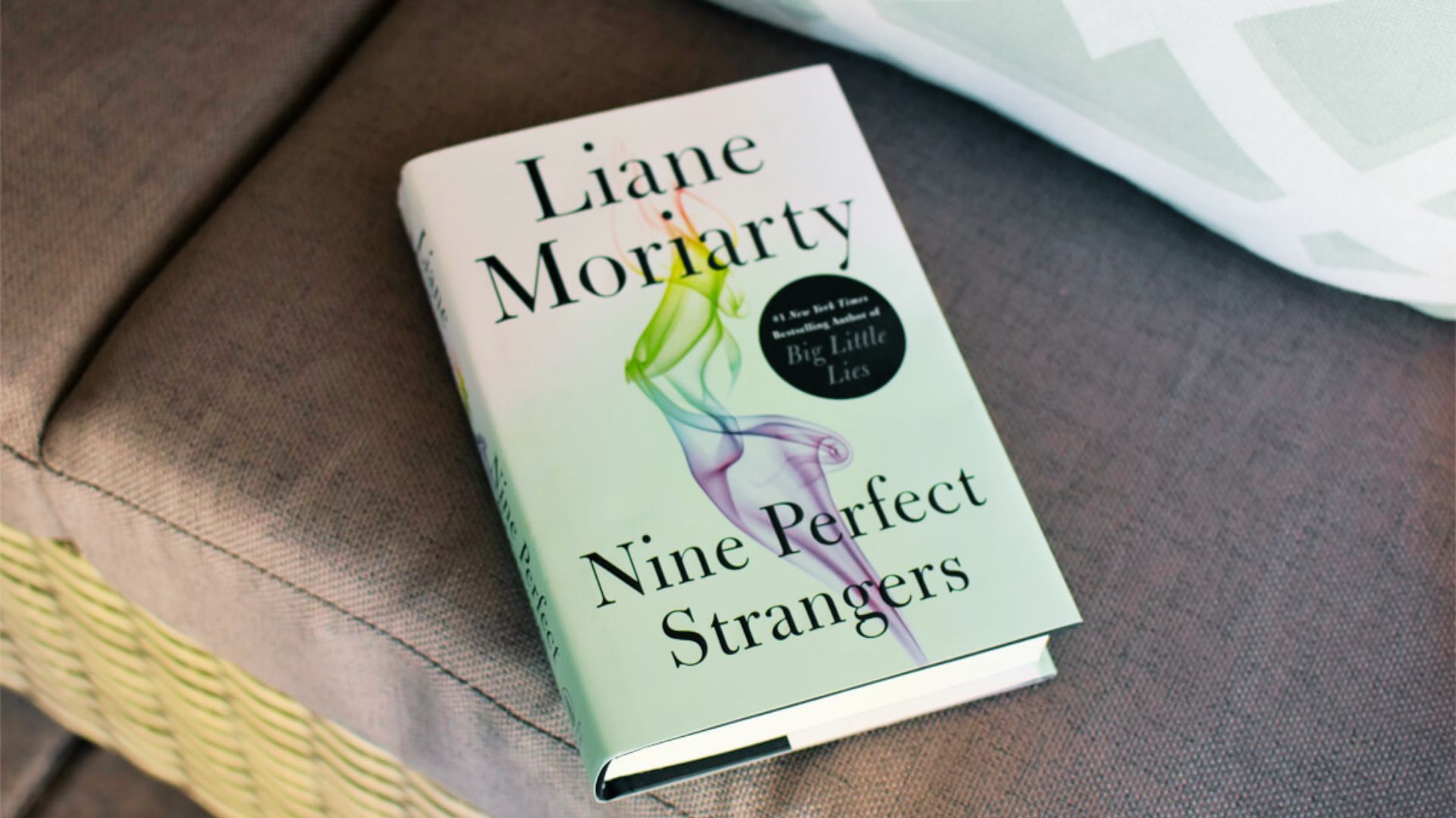 Cover of "Nine Perfect Strangers" by Liane Moriarty, featuring a serene retreat setting with nine diverse characters.