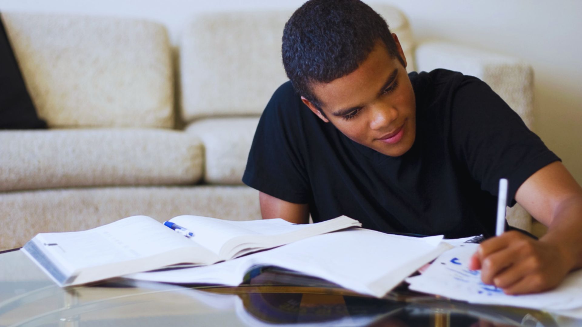 A student studying in a living room, sitting comfortably and focused on their work.