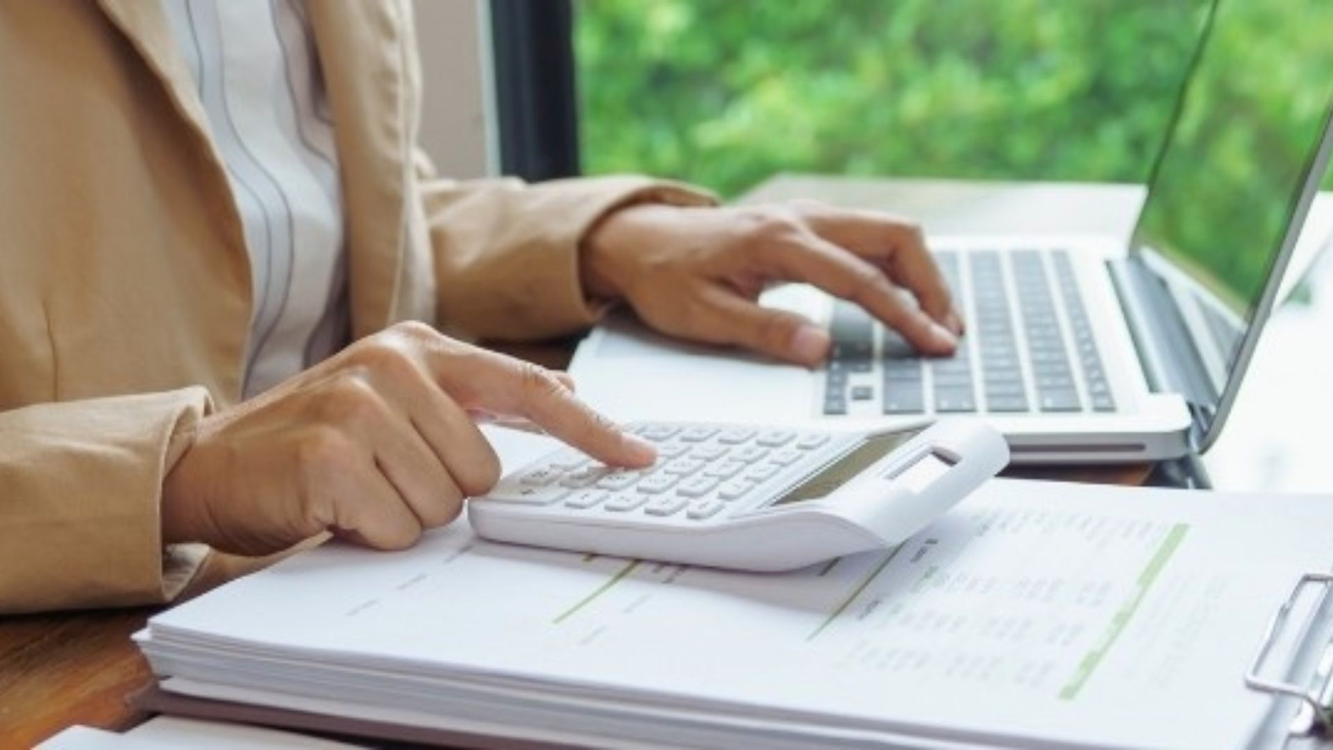 A woman calculates her payment amount using a calculator, focused on her financial task.