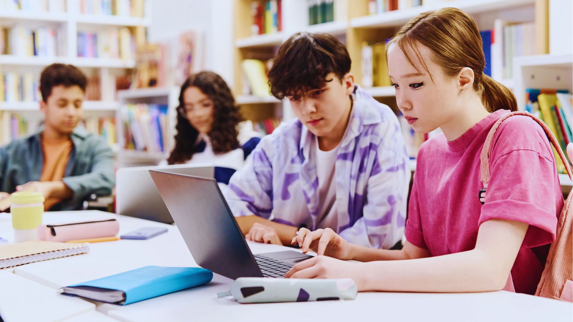 Two people working together on a laptop, collaborating and focused on the screen.