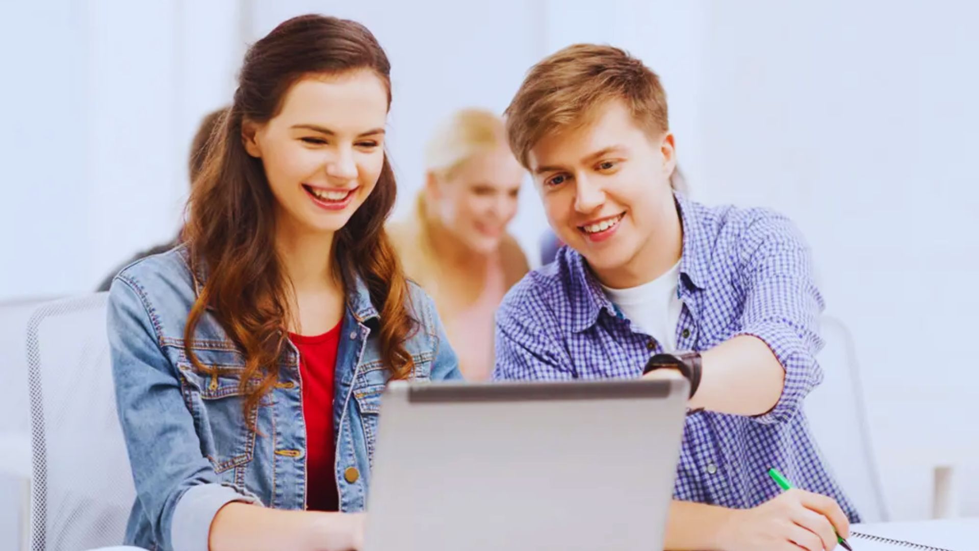 A girl and boy sitting together using a laptop, focused on studying or browsing online.