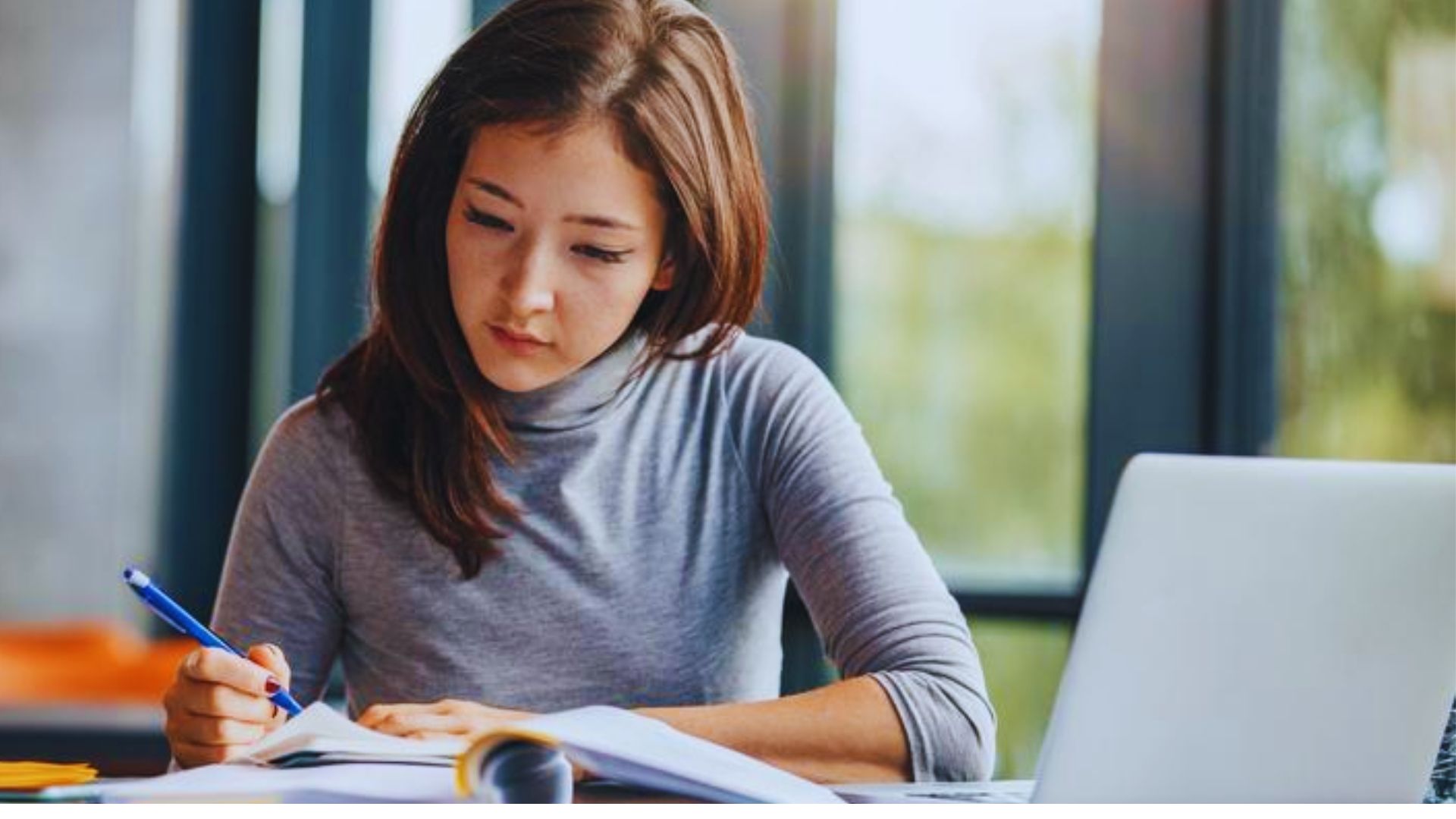A girl studying peacefully, sitting calmly and focused on her work.