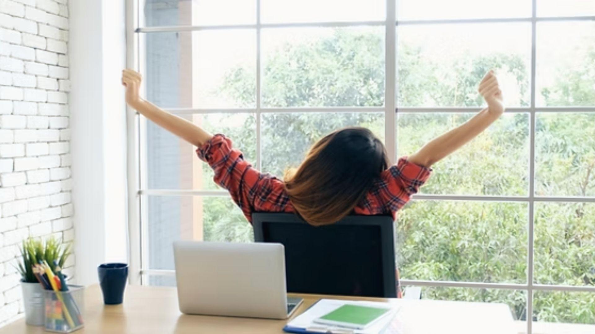 Woman stretches by window after study session, showing short breaks help maintain homework focus.