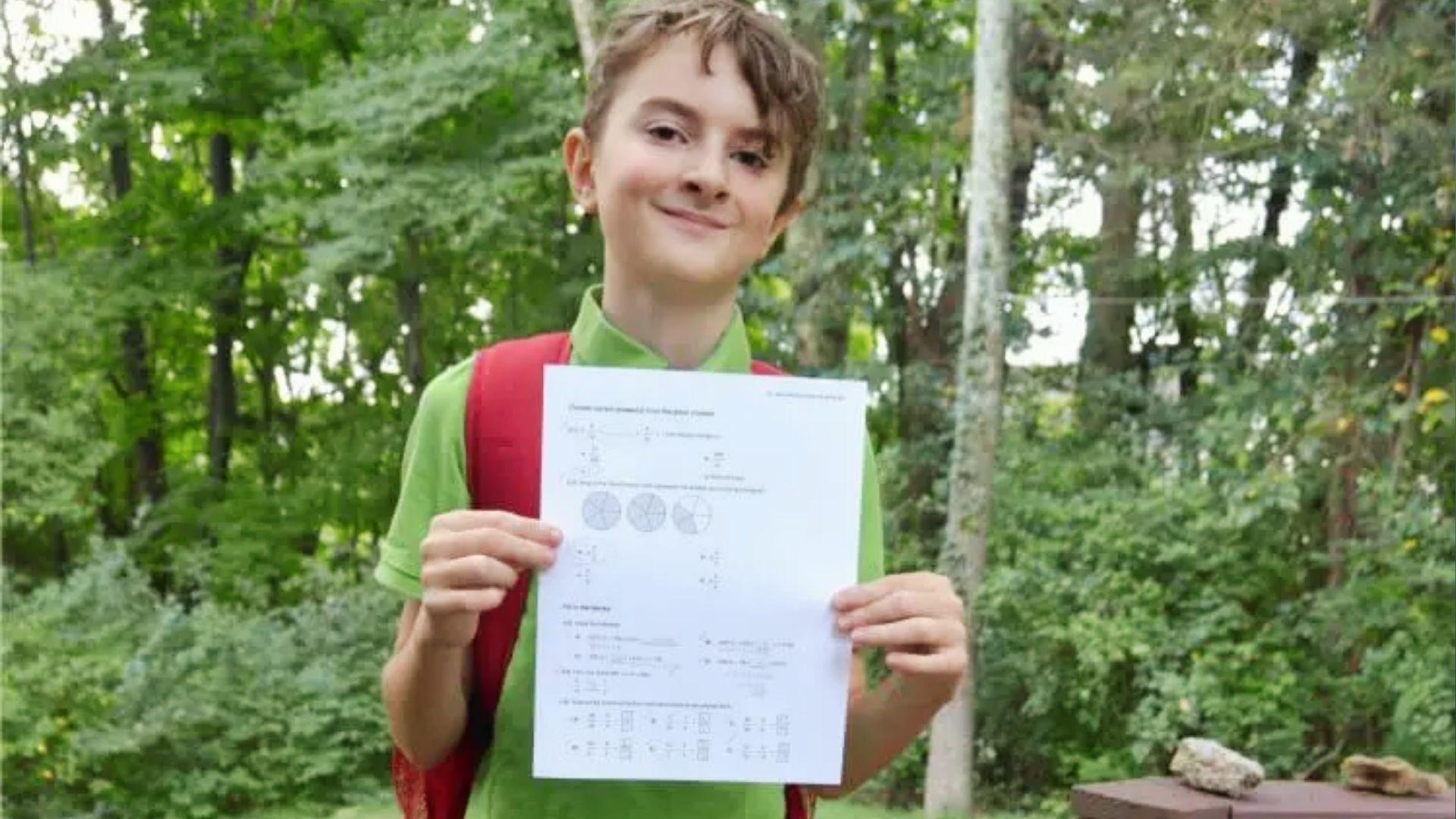 Smiling middle school boy holding completed math worksheet outdoors to celebrate academic effort.