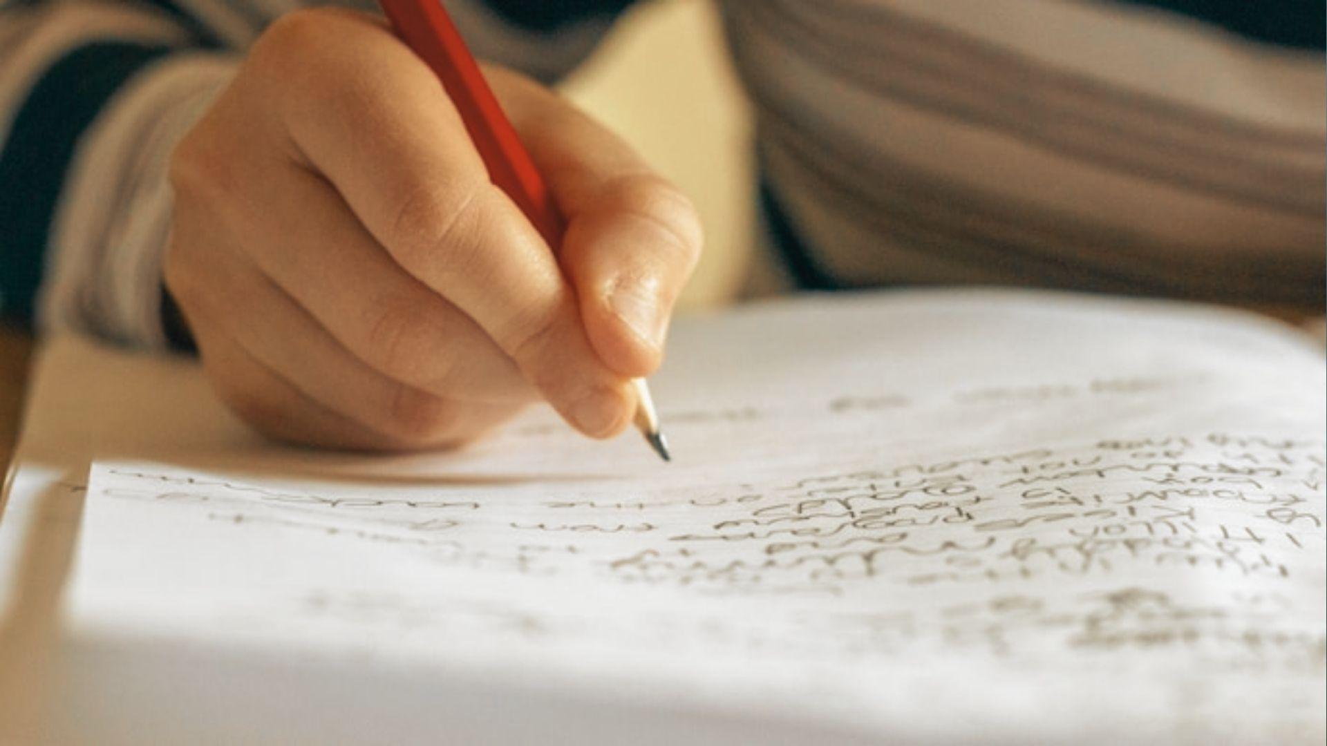 A child's hand gripping red pencil writes on paper, showing focused practice builds handwriting skills.