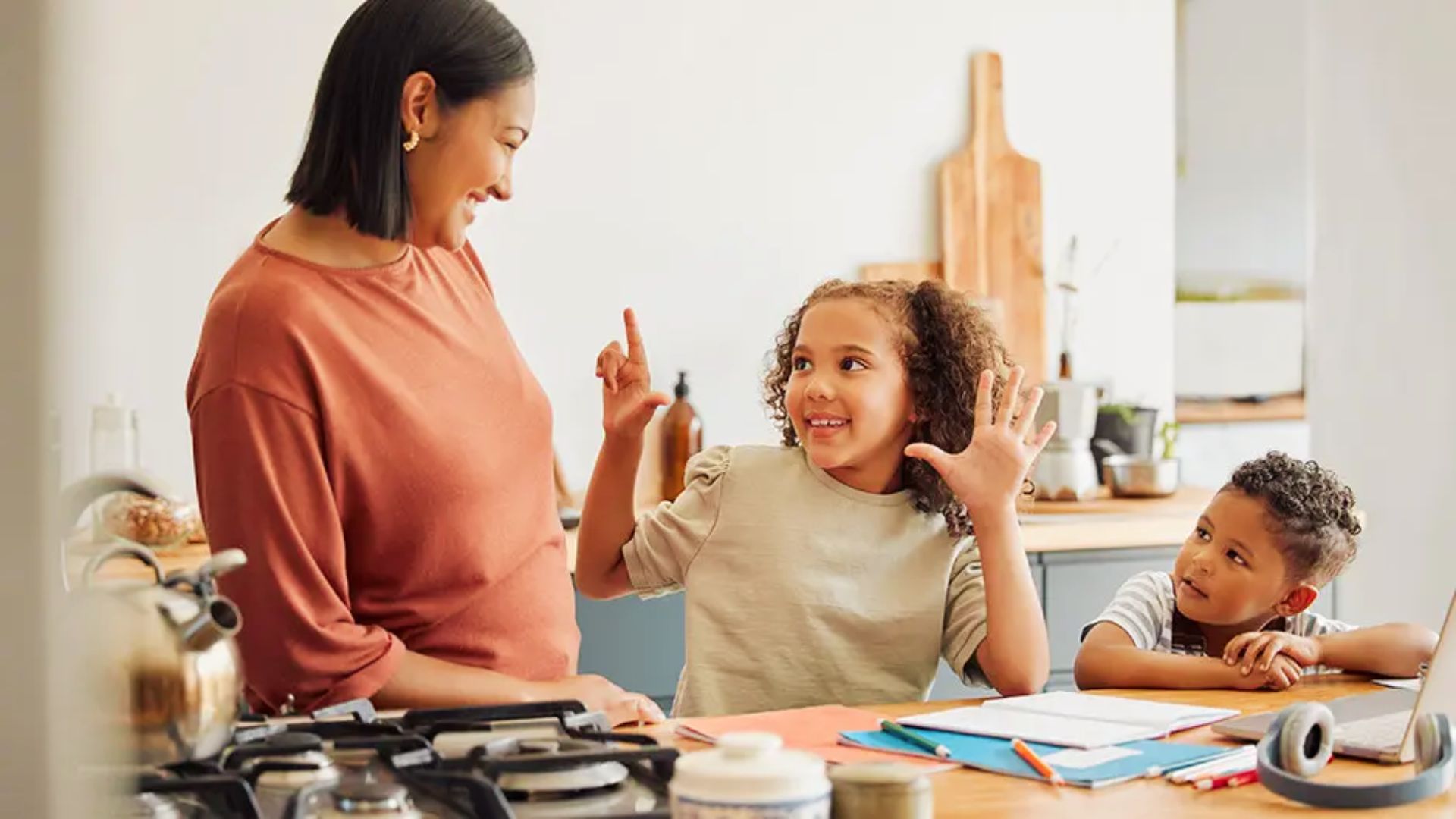 A woman and two children sit together at a kitchen table, discussing options for choosing a homeschool program.