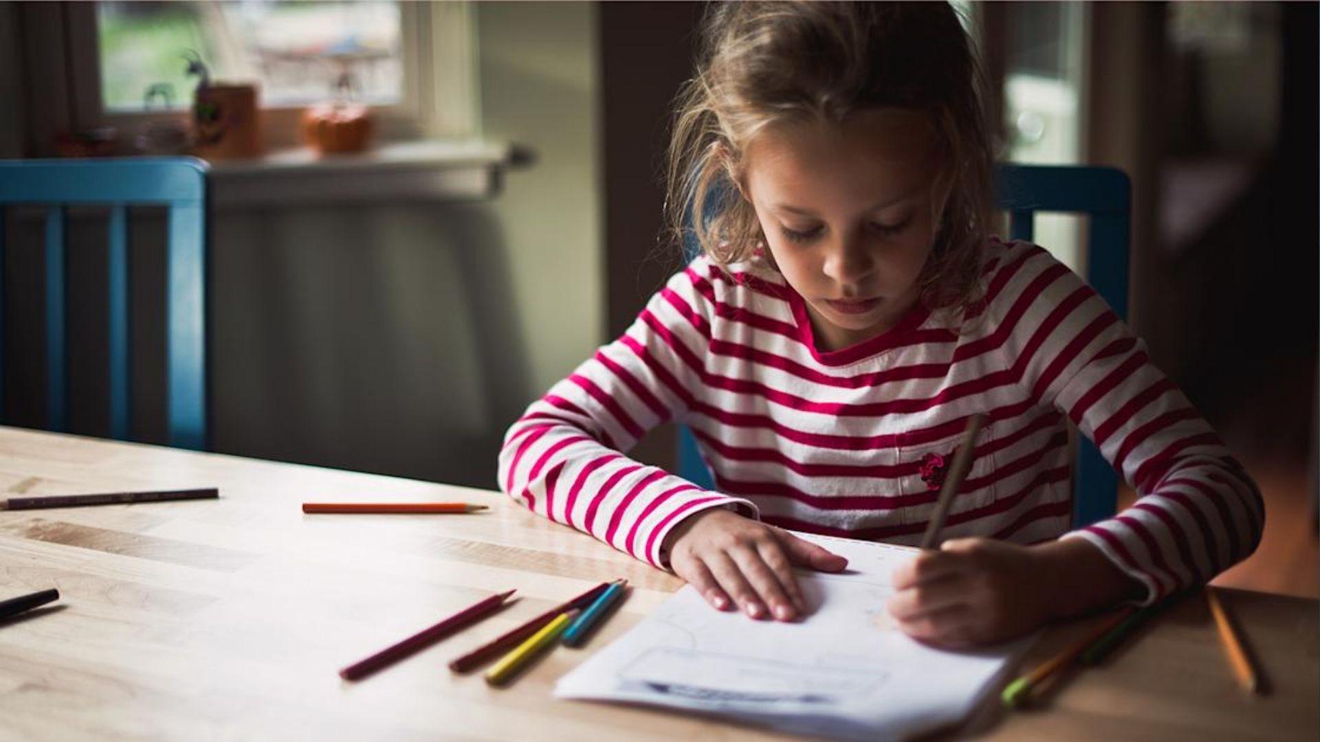 The girl in the striped shirt focuses on drawing at desk, showing calm posture improves handwriting flow.