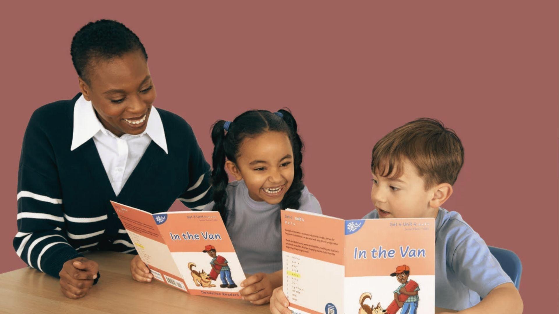 An educator and two children smile while reading decodable books titled "In the Van" together.