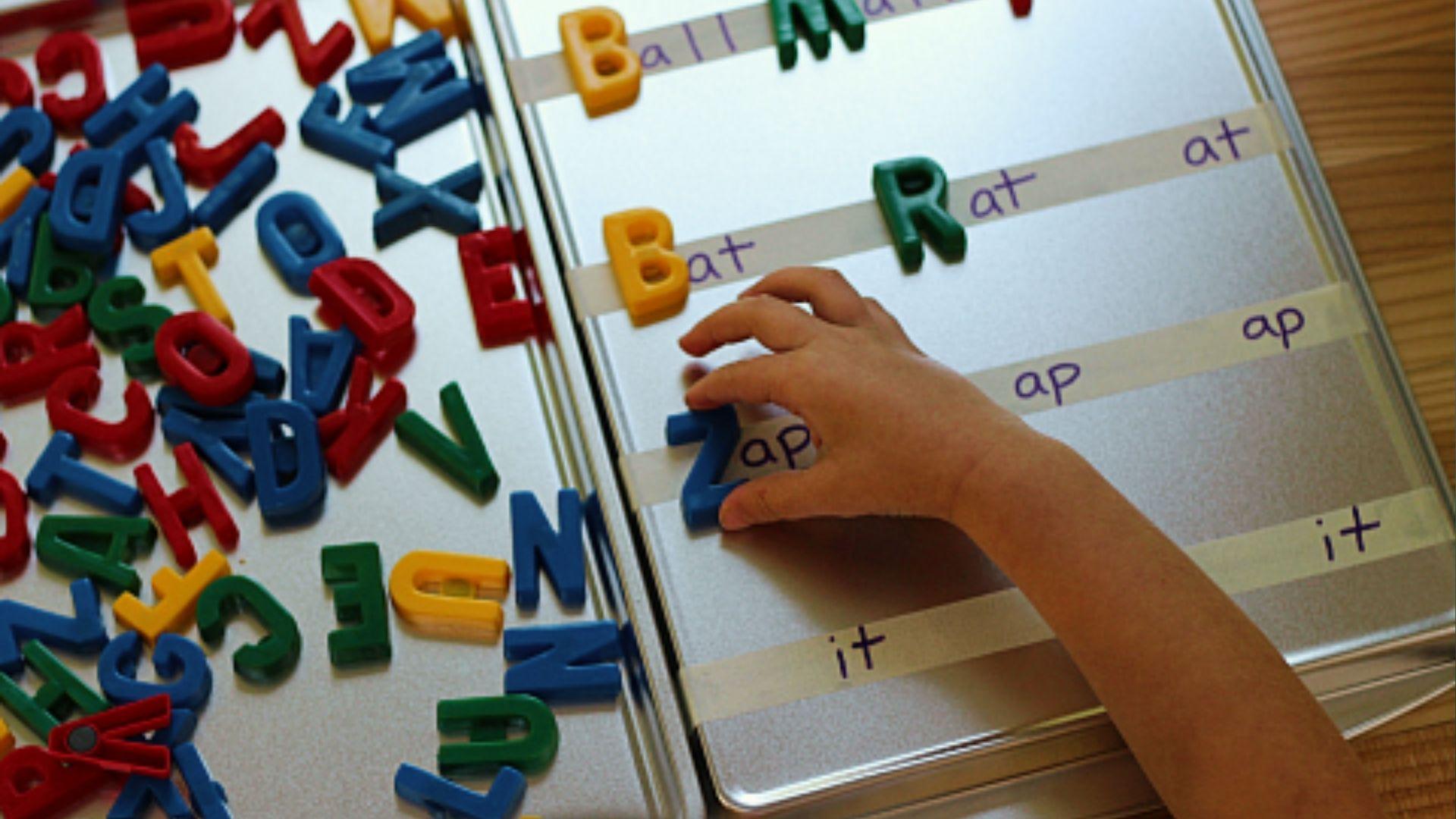 Child places magnetic letters to form words like bat and rat on board for phonics spelling