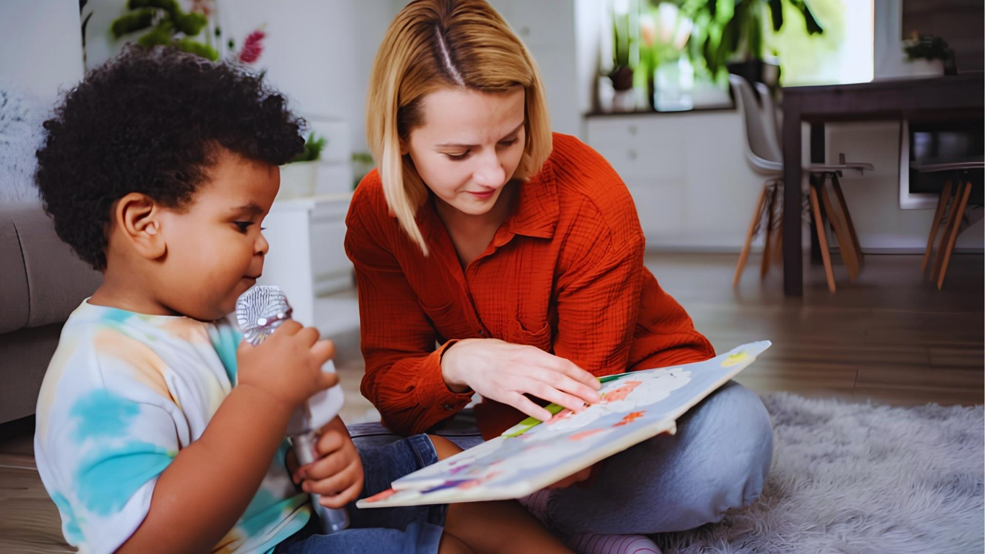 Woman in orange shirt helping toddler with curly hair read colorful book while he holds toy microphone.