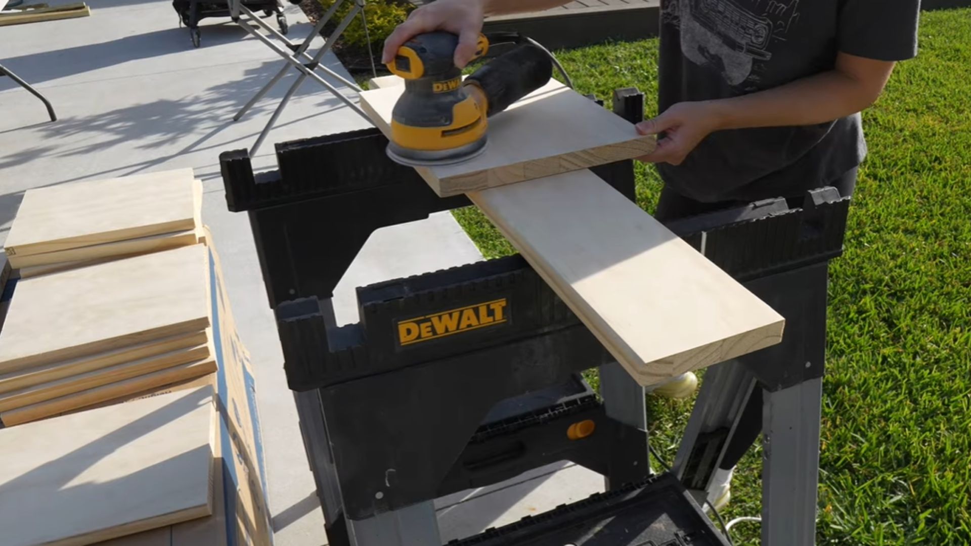 "A man operates a sander, smoothing a piece of wood in a workshop setting."