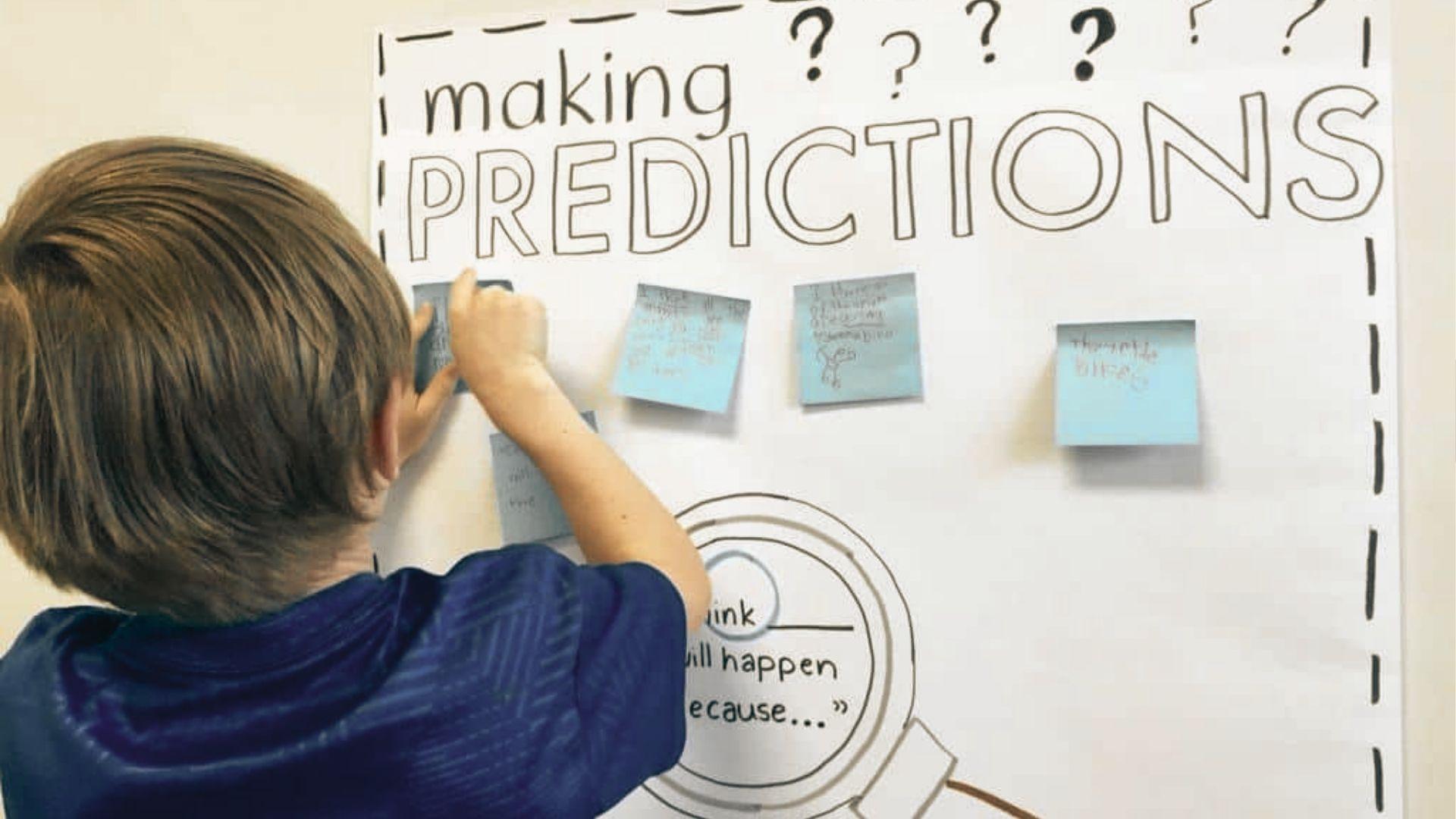 Young student places sticky notes on a "Making Predictions" chart with magnifying glass and question marks.