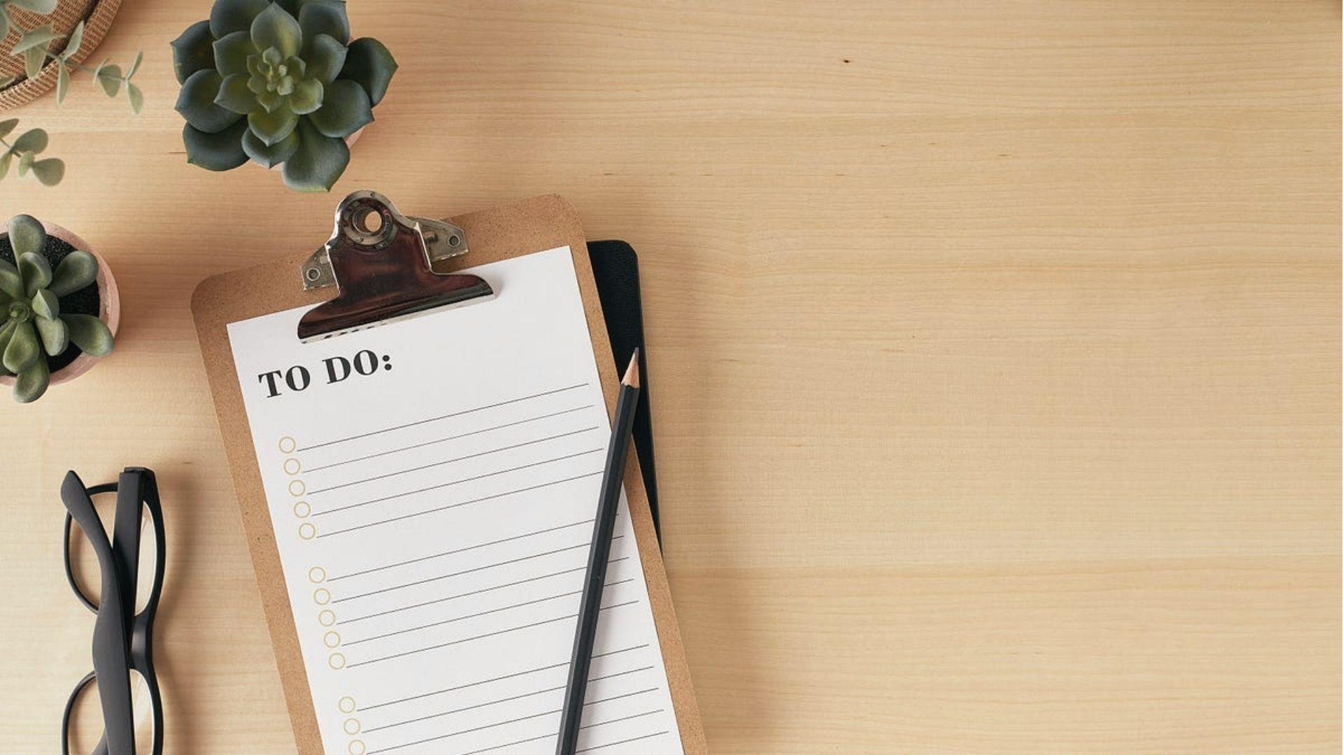 Clipboard with blank to-do list, glasses, and plants, showing task lists beat homework procrastination.