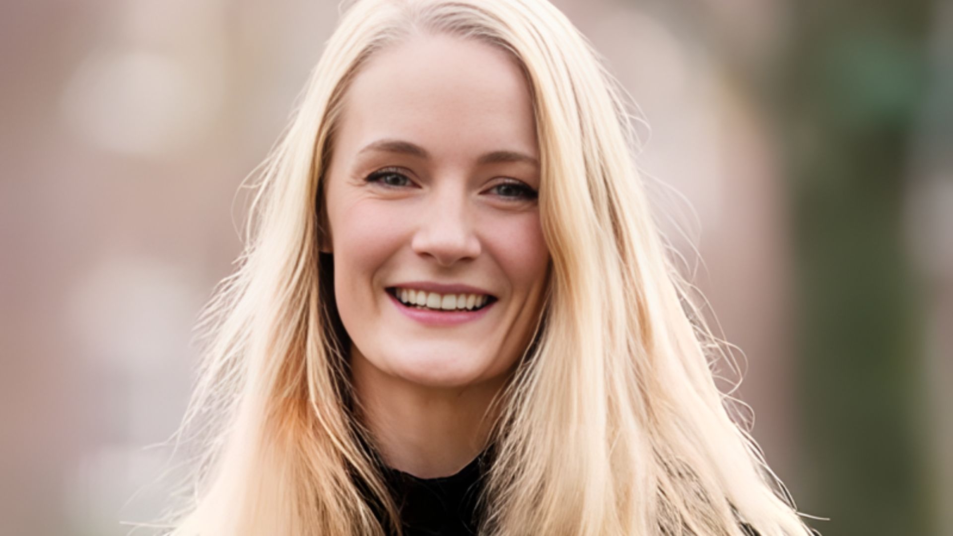 A smiling Lucy Foley, author of The Guest List, showcases her long blond hair, radiating positivity and charm.