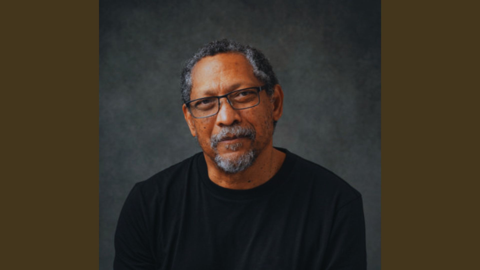 Author wearing glasses and a black shirt, looking directly at the camera with a neutral expression