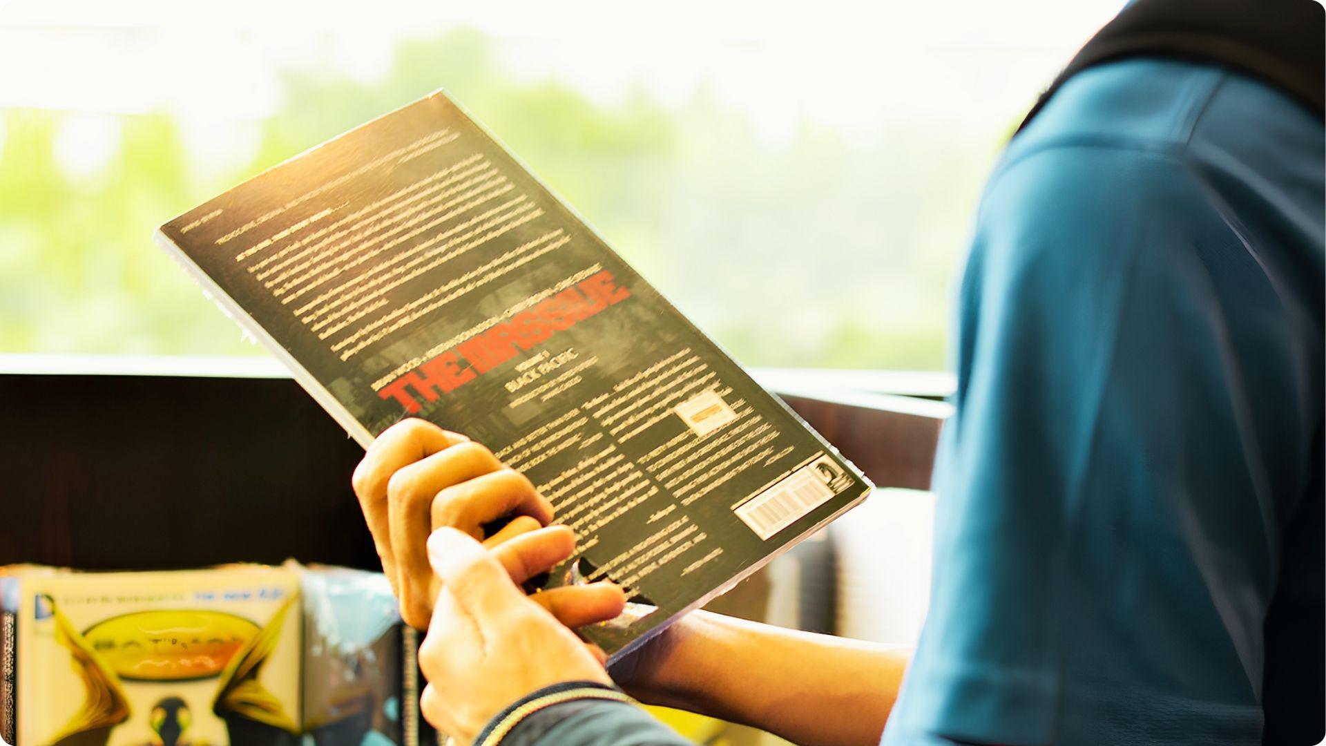Person in a blue shirt holding a book titled The Imps to read the text on the back cover.