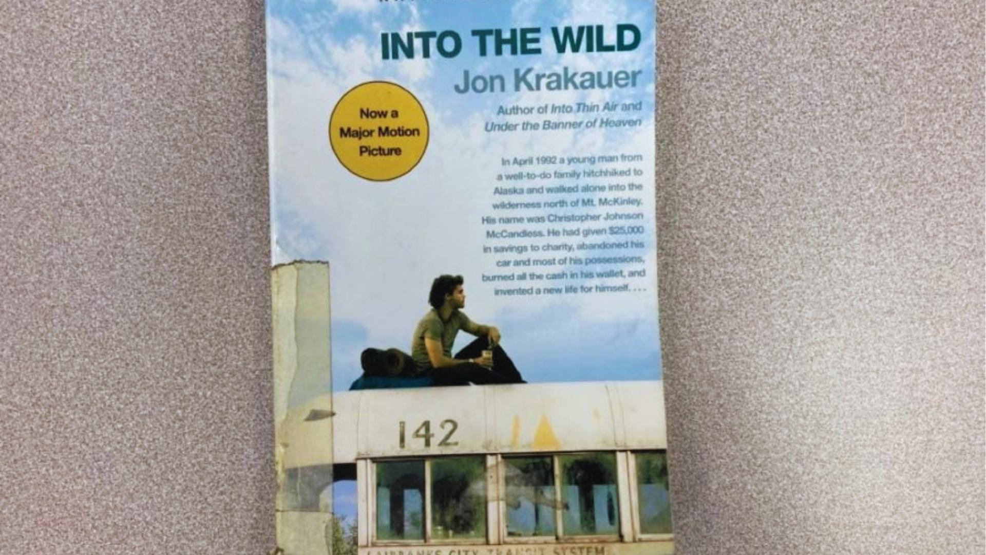 Cover of Into the Wild paperback featuring Christopher McCandless sitting atop Bus 142 with book summary about Alaska journey.