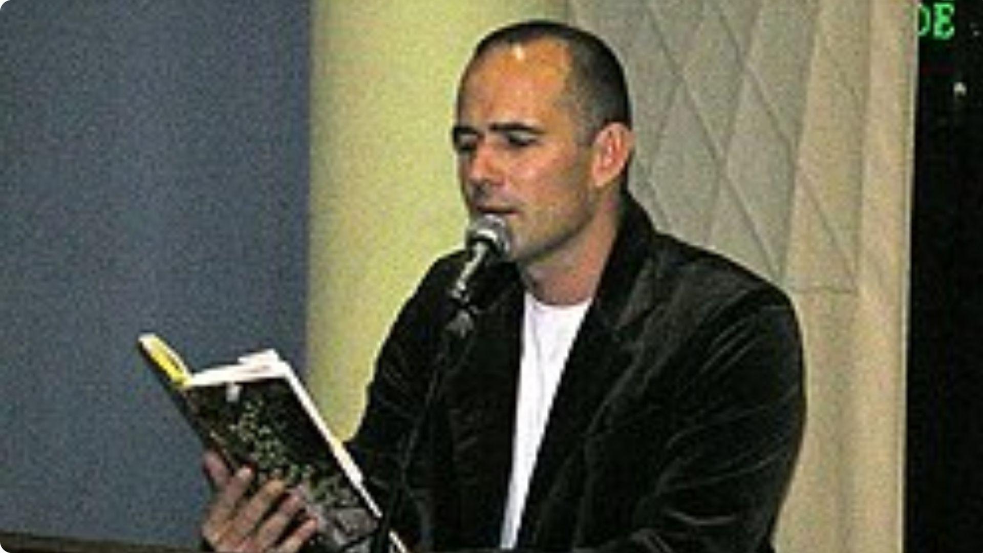 The author reading from one of his books at a microphone during a literary event.