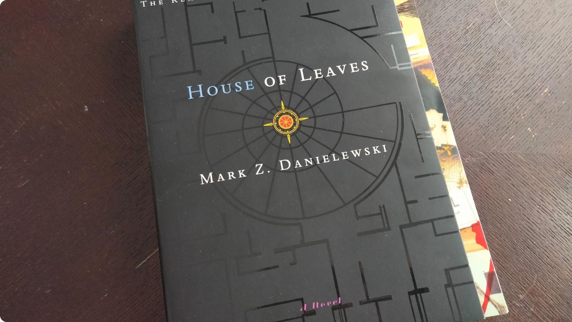 Copy of "House of Leaves" by Mark Z. Danielewski lying on a dark wooden surface.