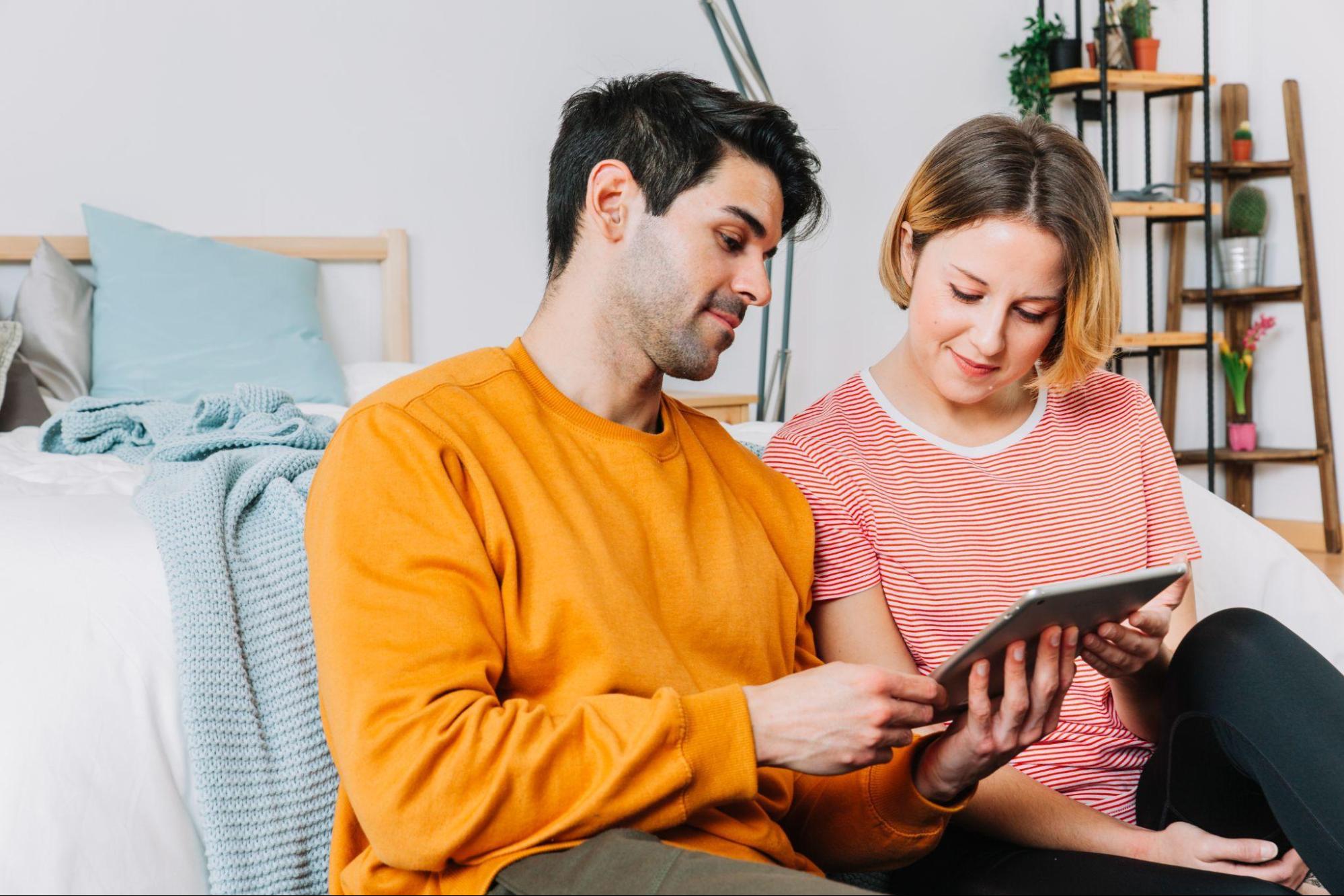 Beautiful couple using tablet near bed watching webtoons in a tablet